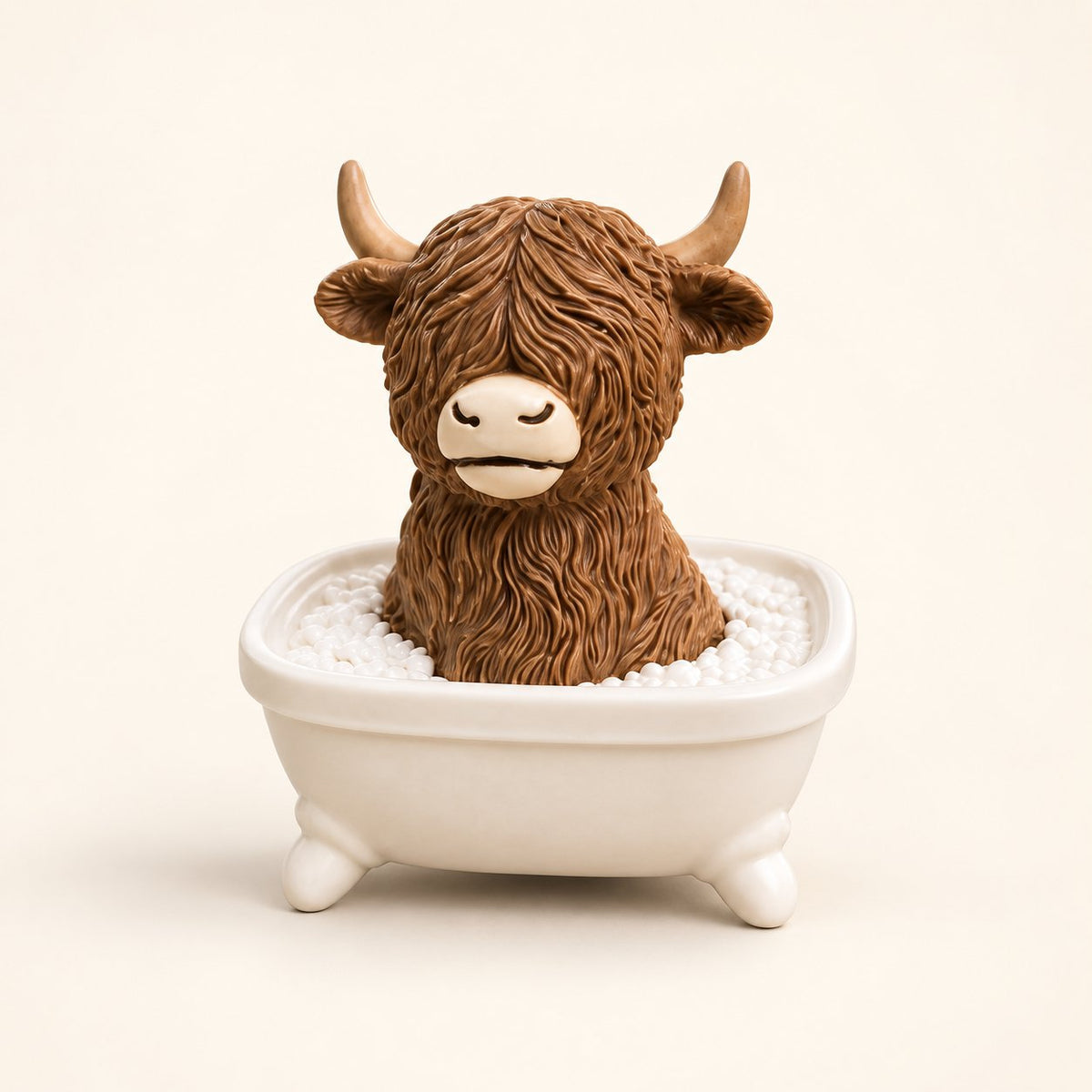 Brown Highland cow figurine sitting in a cream bathtub with sculpted white bubbles, on an ivory background.