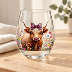 Flower-field Highland cow glass on pale timber with ivory linen and eucalyptus; styling props are not included.