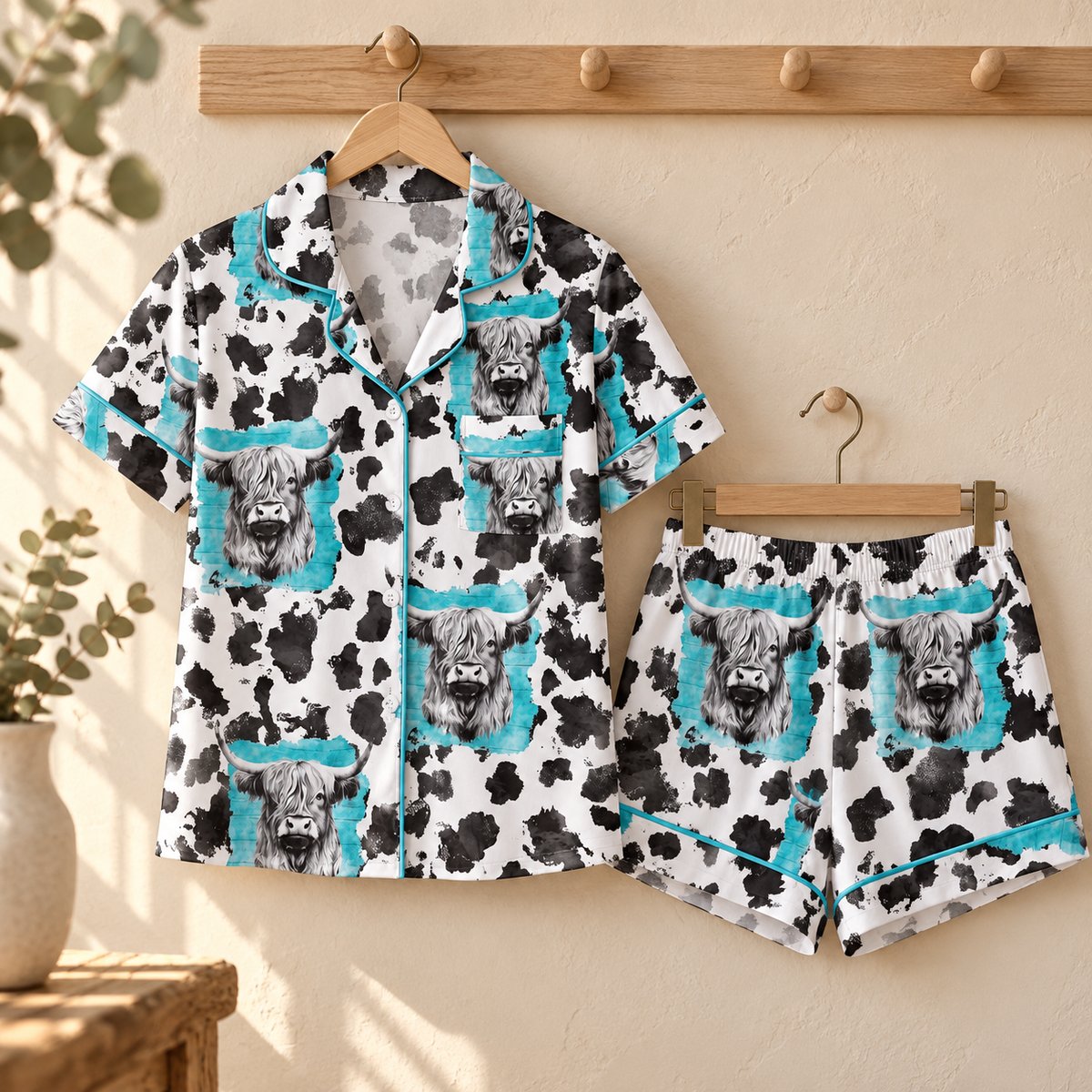 Blue Highland cow button-up pyjama shirt and matching shorts displayed on wooden hangers