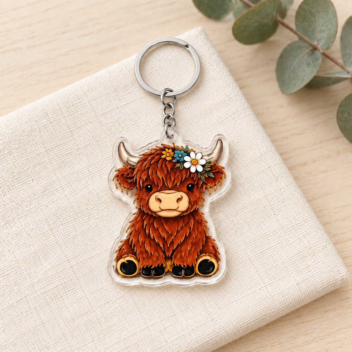 Daisy Crown Highland cow acrylic keyring styled on ivory linen; props not included