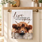 Live Like Someone Left the Gate Open Highland cow tea towel hanging in a cream country kitchen
