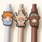 Close-up of three Highland cow pen toppers showing assorted printed rubber designs