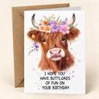 Buttloads of Fun Highland cow birthday card with a colourful flower crown, shown with one kraft envelope.