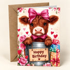 Pink Bow Birthday Highland cow card with a calf in a bucket, pink flowers and gifts, shown with one kraft envelope.