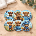 Six blue Highland cow coasters styled on pale timber with cream linen and eucalyptus; decorative props are not included.