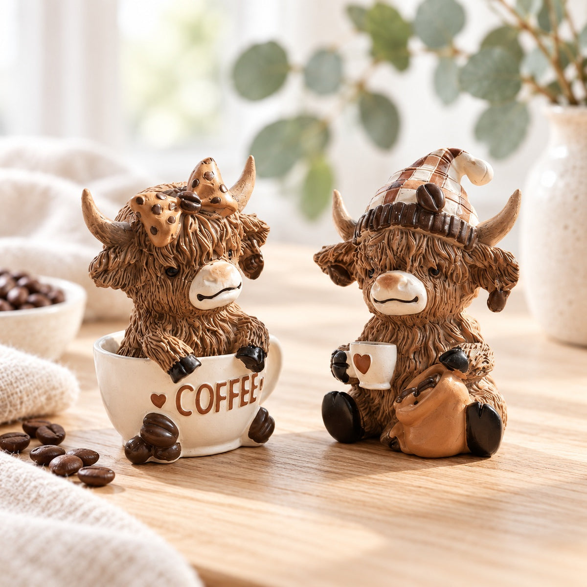 Highland cow Coffee Cup and Coffee Beans figurines displayed together in a cosy coffee-corner setting. Sold individually.