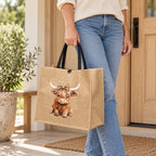 Styled lifestyle image of a woman holding the khaki Highland cow leopard-bow tote by its black handles outside a doorway.