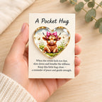 Hand holding the pink bow Highland cow pocket hug and message card over pale timber