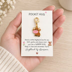 Pocket Hug calf keyring and message card held in a hand to show small gift size