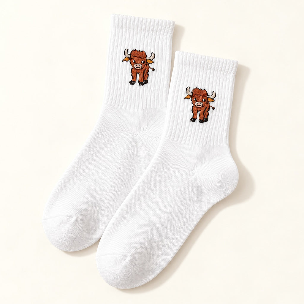 One pair of white Highland cow socks with ribbed cuffs and a small cow motif, shown on an ivory background.