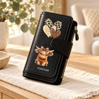 Black Highland cow long wallet with leopard hearts and bow on a warm neutral tabletop