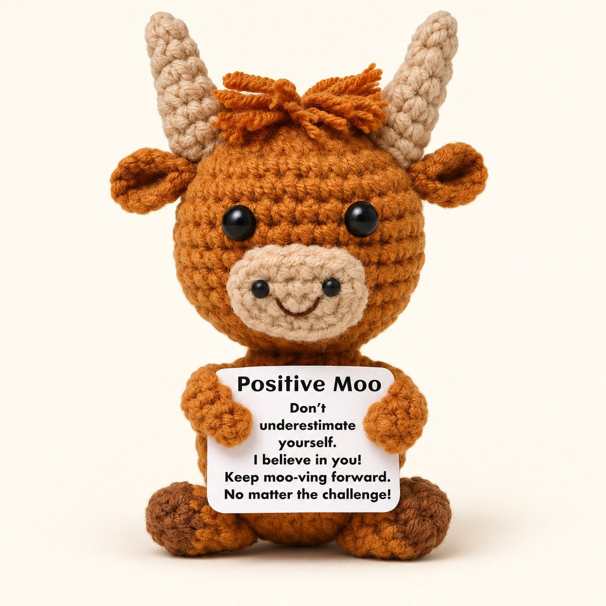 Brown mini knitted Highland cow holding a white Positive Moo encouragement card