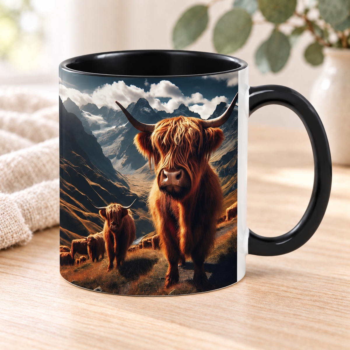 One Realistic Mountain Highland Cow Mug with black handle and interior, styled on pale timber with ivory linen and eucalyptus; decorative props are not included.