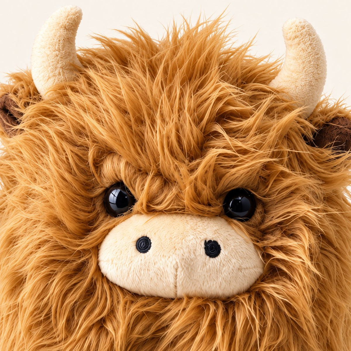 Close-up of the brown plush cow’s shaggy fur, glossy black eyes and beige muzzle