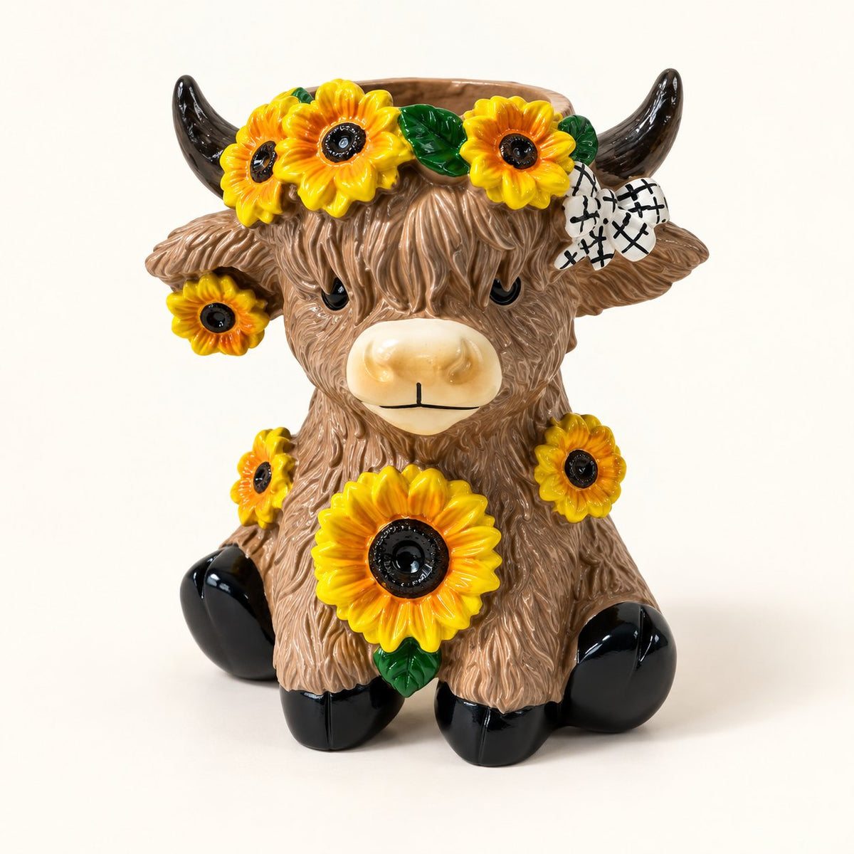 Sunflower Highland cow mini planter with yellow flowers, black horns and a white patterned bow on an ivory background